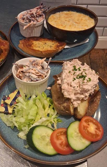 A jacket potato topped with tuna mayo, with coleslaw, salad and butter